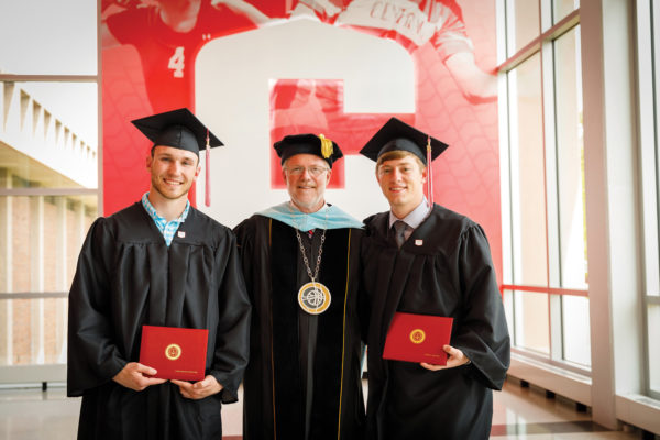 Central College President Mark Putnam poses for a photo with the first two graduates of Central's engineering program.