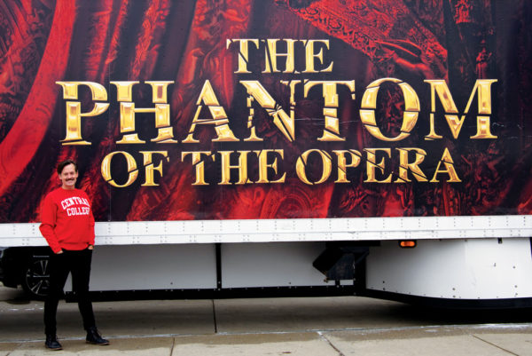 Rob Lindley '95 standing beside a trailer advertising "The Phantom of the Opera"